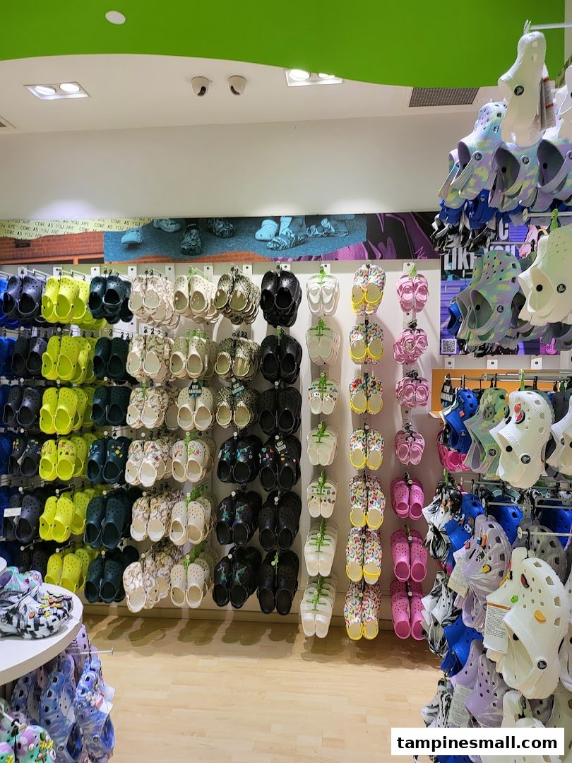 A vibrant wall display showcasing a wide variety of colorful Crocs clogs and sandals in a retail store.