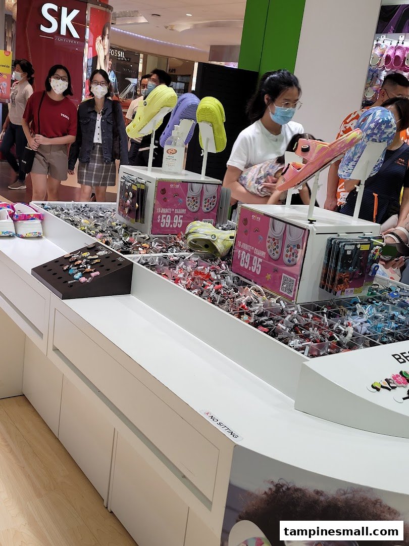 A vibrant display of Crocs Jibbitz charms and footwear inside a bustling mall environment.