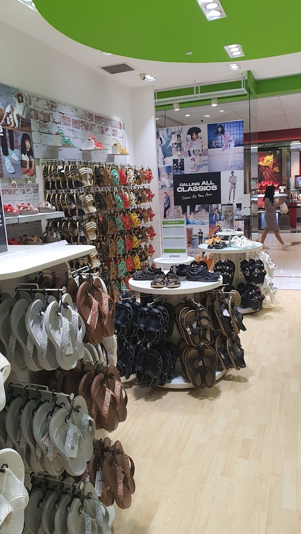An interior view of the Crocs store, showcasing a wide variety of colorful footwear and sandals.