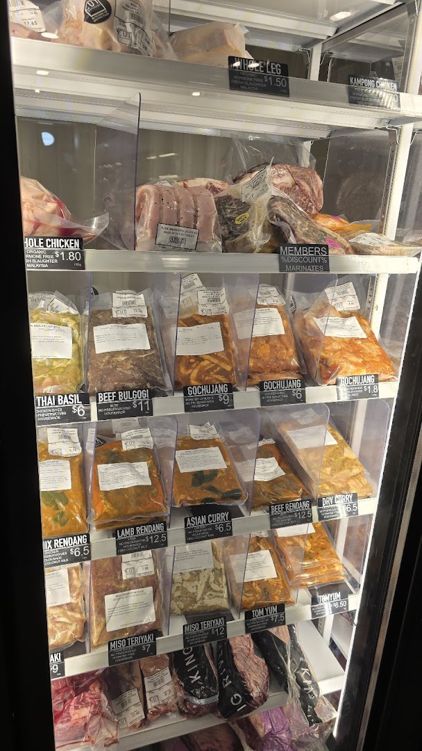 A refrigerated display case showcasing various packaged meats, marinated cuts, and their prices at Cut Butchery.