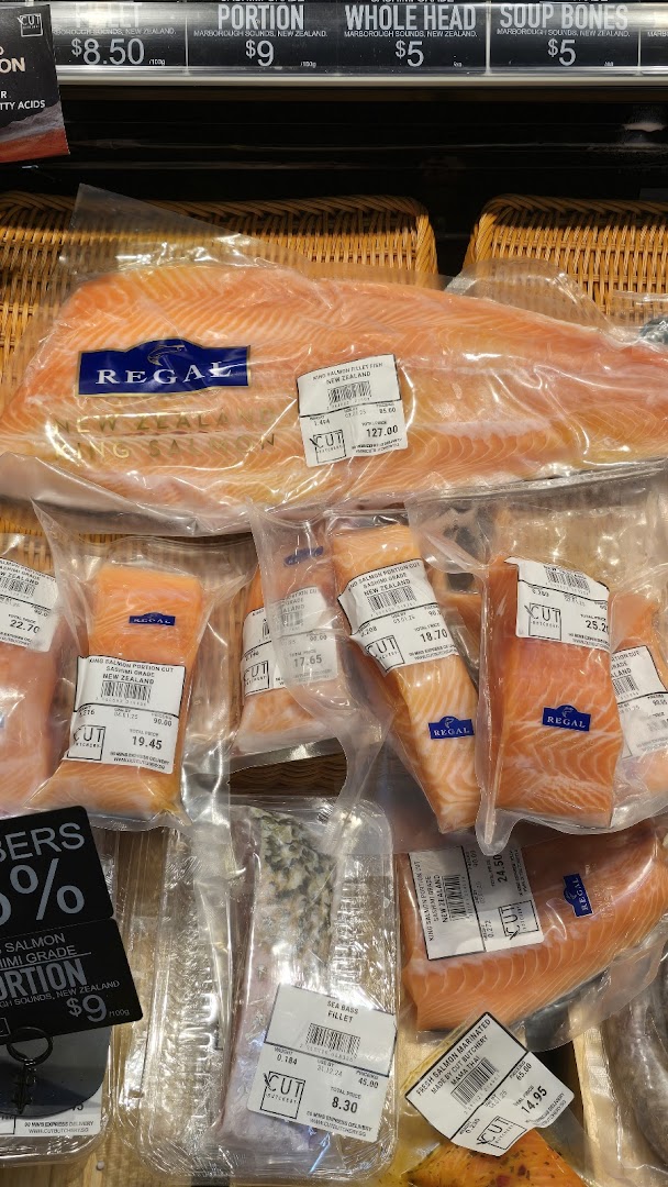 Various cuts of fresh, packaged salmon and other seafood displayed in a retail chiller.