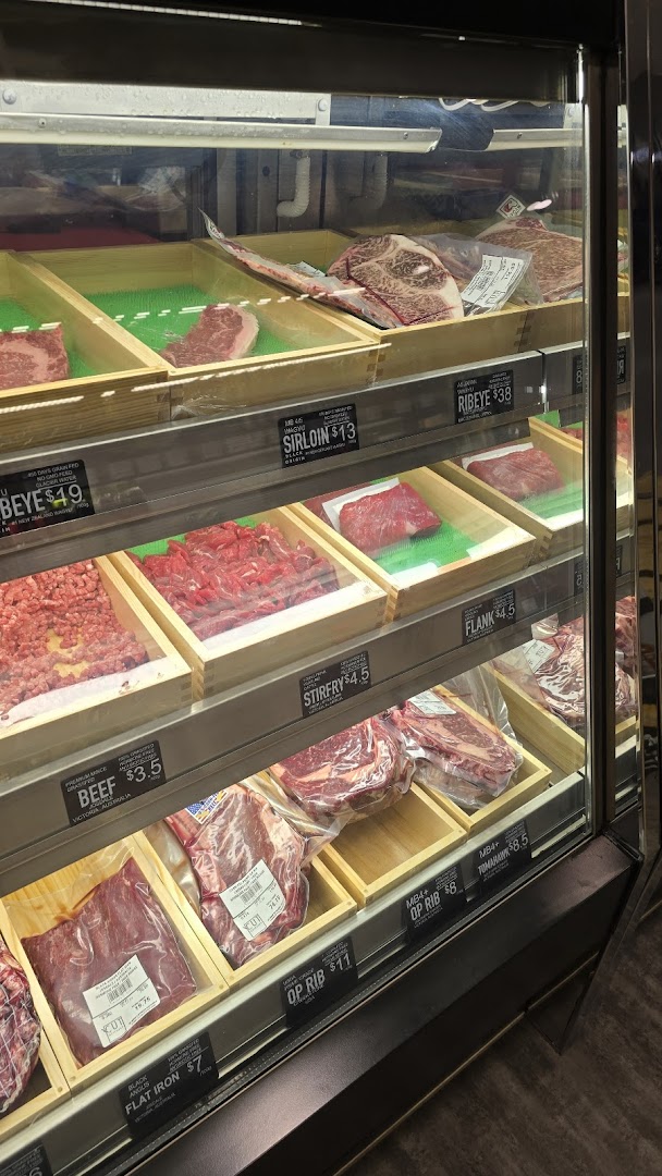 A refrigerated display case showcasing various cuts of fresh meat with clear price labels.