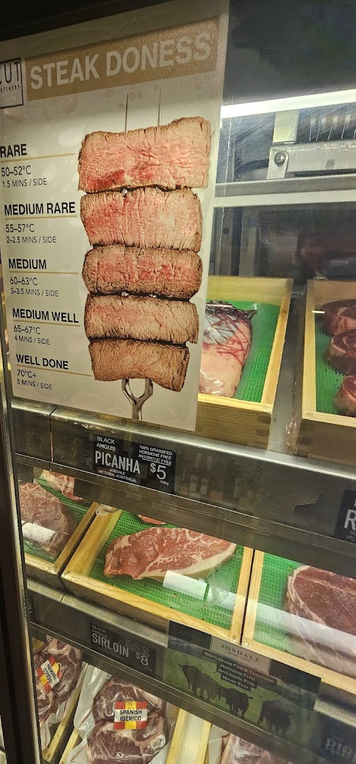 A display case at Cut Butchery showcasing various meat cuts and a steak doneness guide.