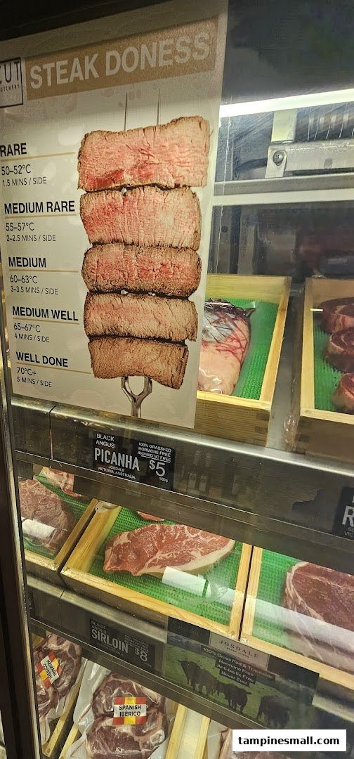 A display case at Cut Butchery showcasing various meat cuts and a steak doneness guide.