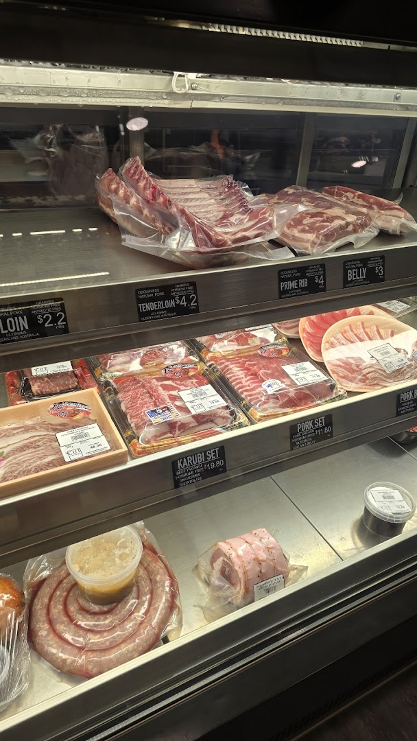 A refrigerated display case filled with various fresh meat cuts and sausages at Cut Butchery.