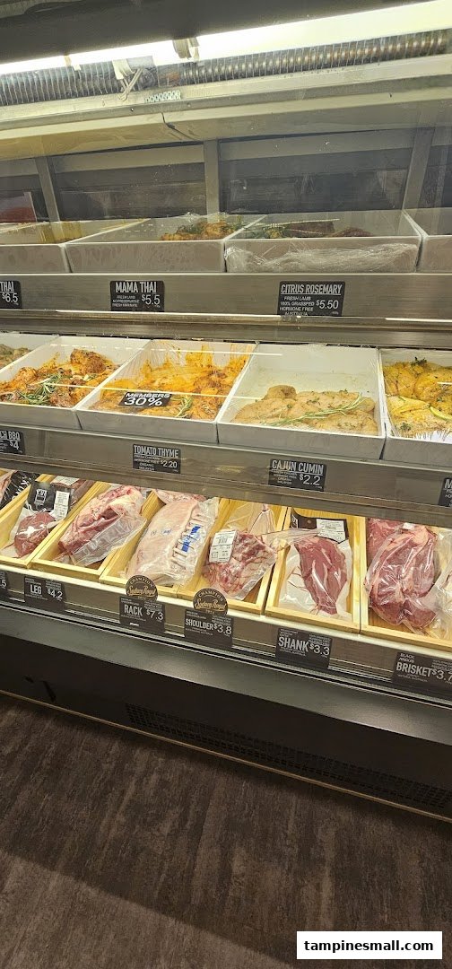 A refrigerated display case showcasing various fresh and marinated meat cuts at a butchery.