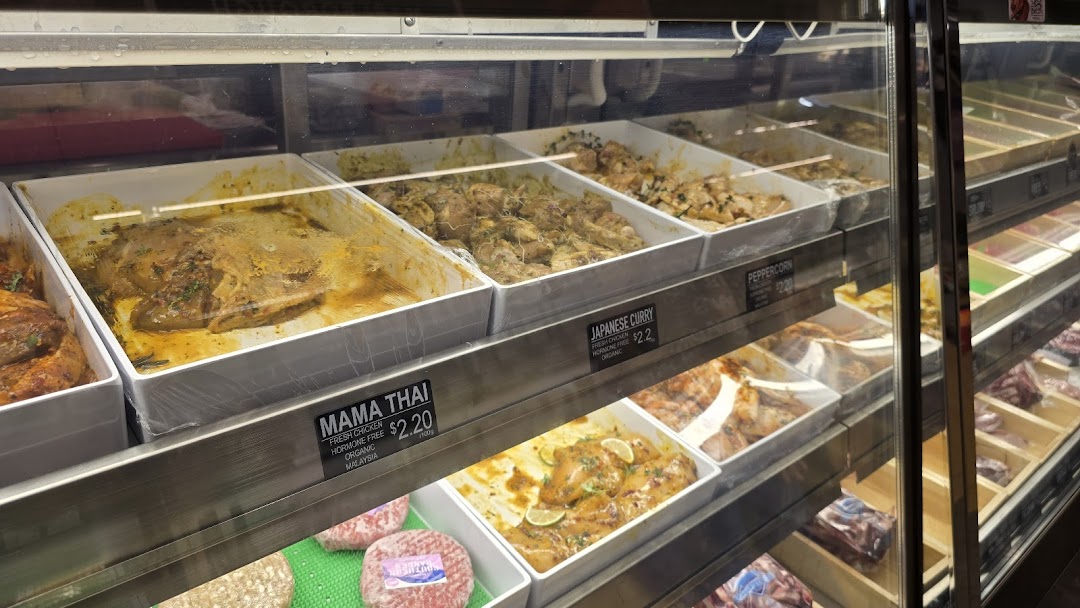 A display case at Cut Butchery showcasing various marinated fresh chicken options like Mama Thai and Japanese Curry.