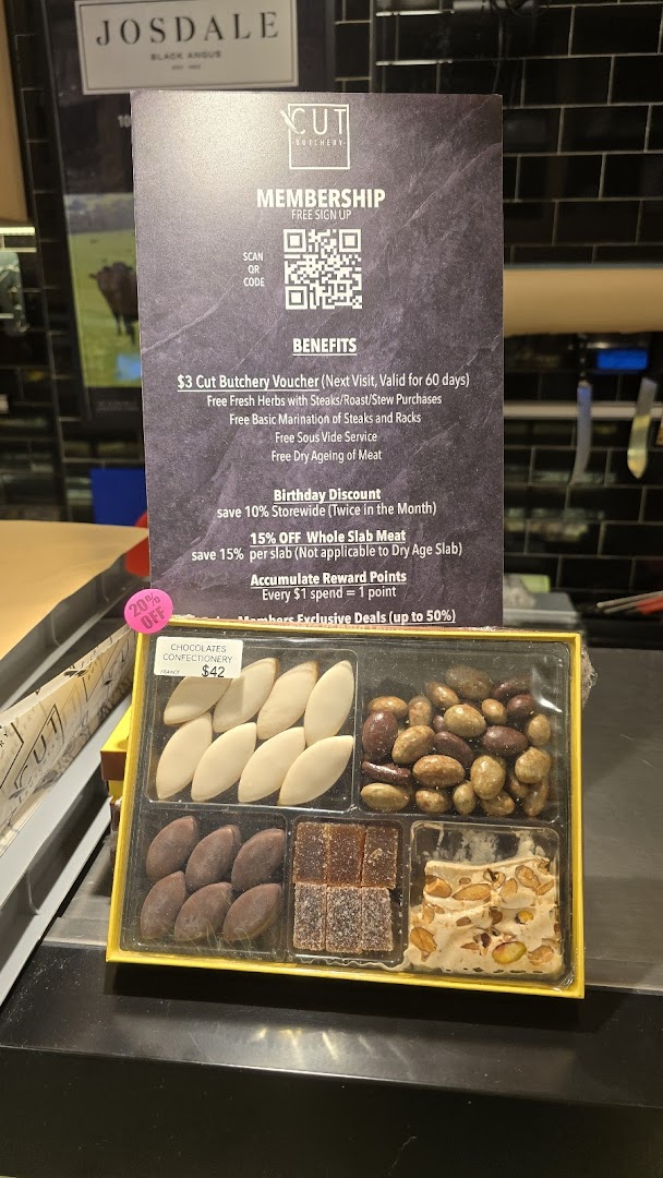 A membership benefits sign and a gourmet confectionery box displayed at Cut Butchery.