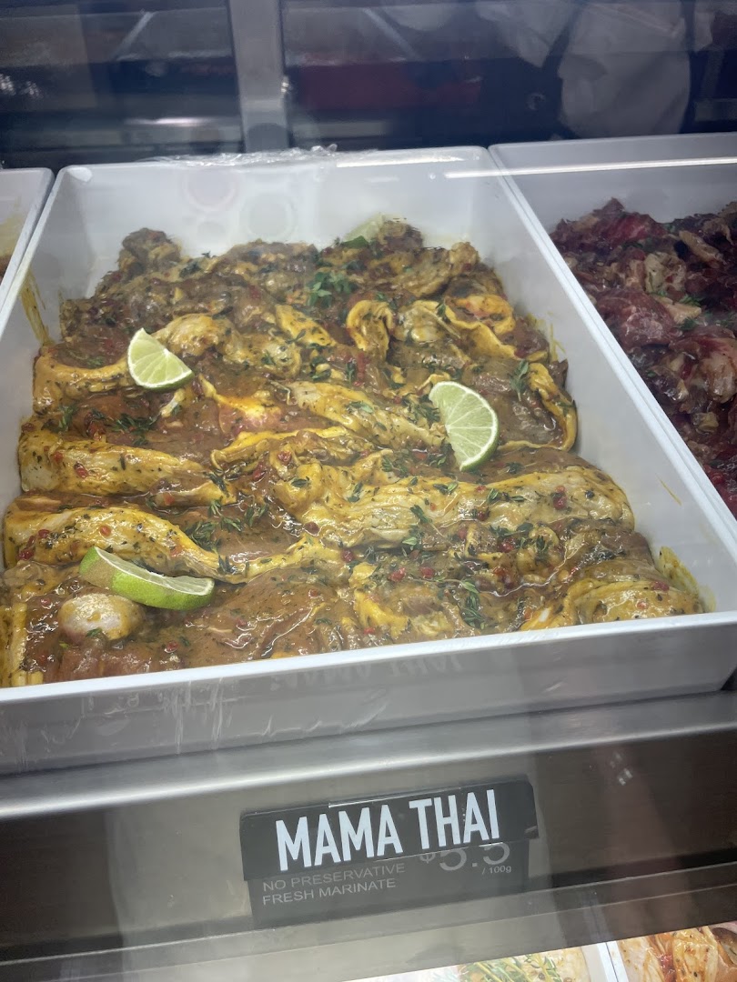 Freshly marinated Mama Thai meat with lime slices displayed in a butchery's chilled case.