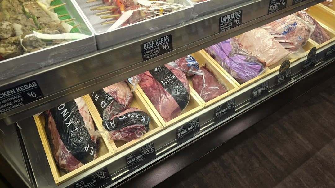 A display case showcasing various fresh meat cuts and kebabs with price labels at Cut Butchery.