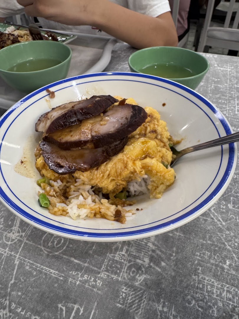 A close-up of scrambled egg rice topped with char siu, served with soup.