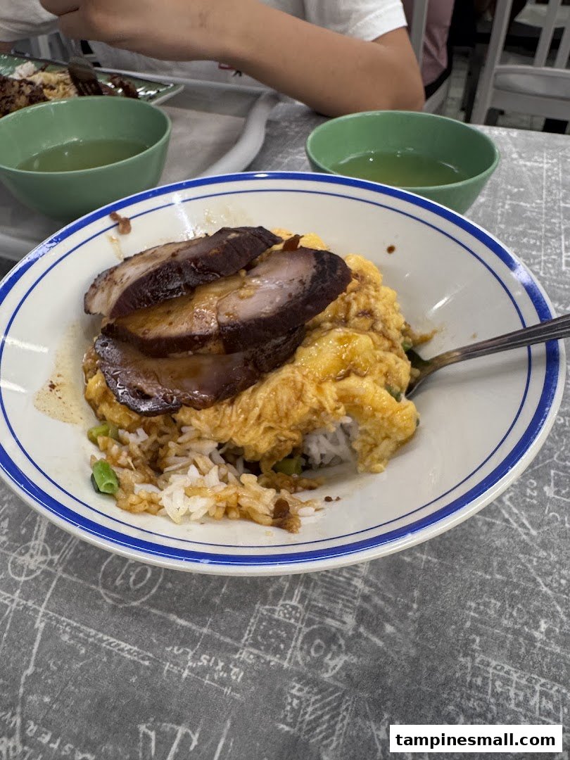 A close-up of scrambled egg rice topped with char siu, served with soup.
