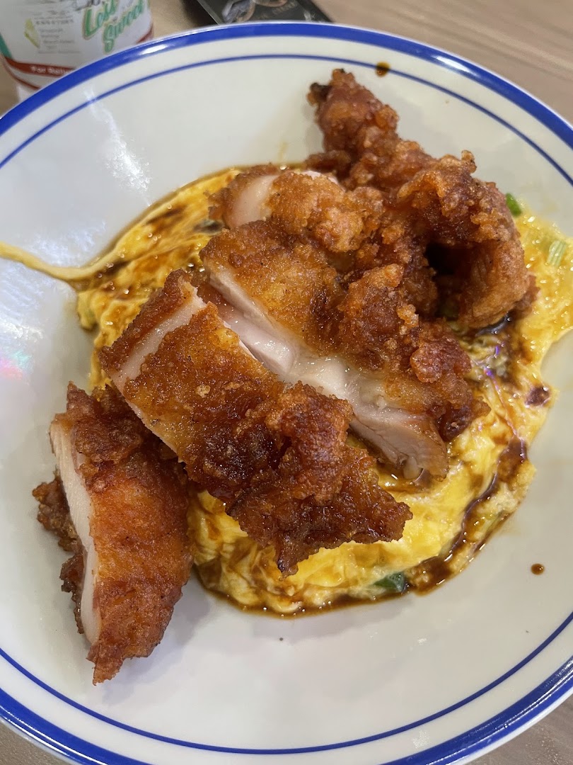 A close-up of crispy fried chicken pieces served over fluffy scrambled egg rice.