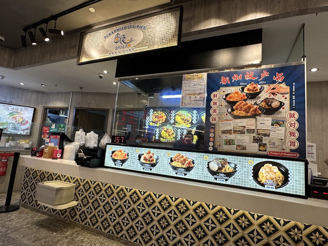 Interior view of Dan Lao Scrambled Egg Rice counter showcasing delicious food displays and branding.