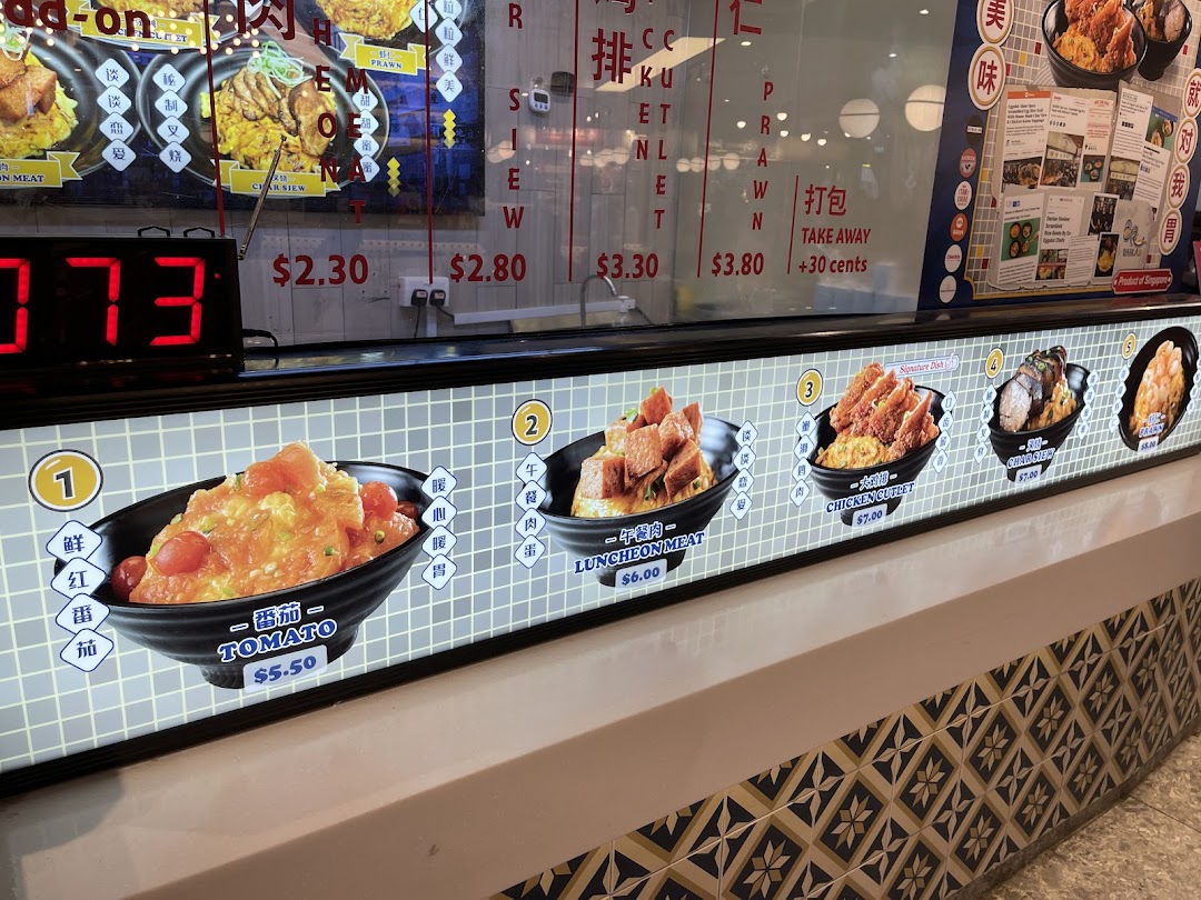 A vibrant display of scrambled egg rice dishes with various toppings and prices at a food stall.
