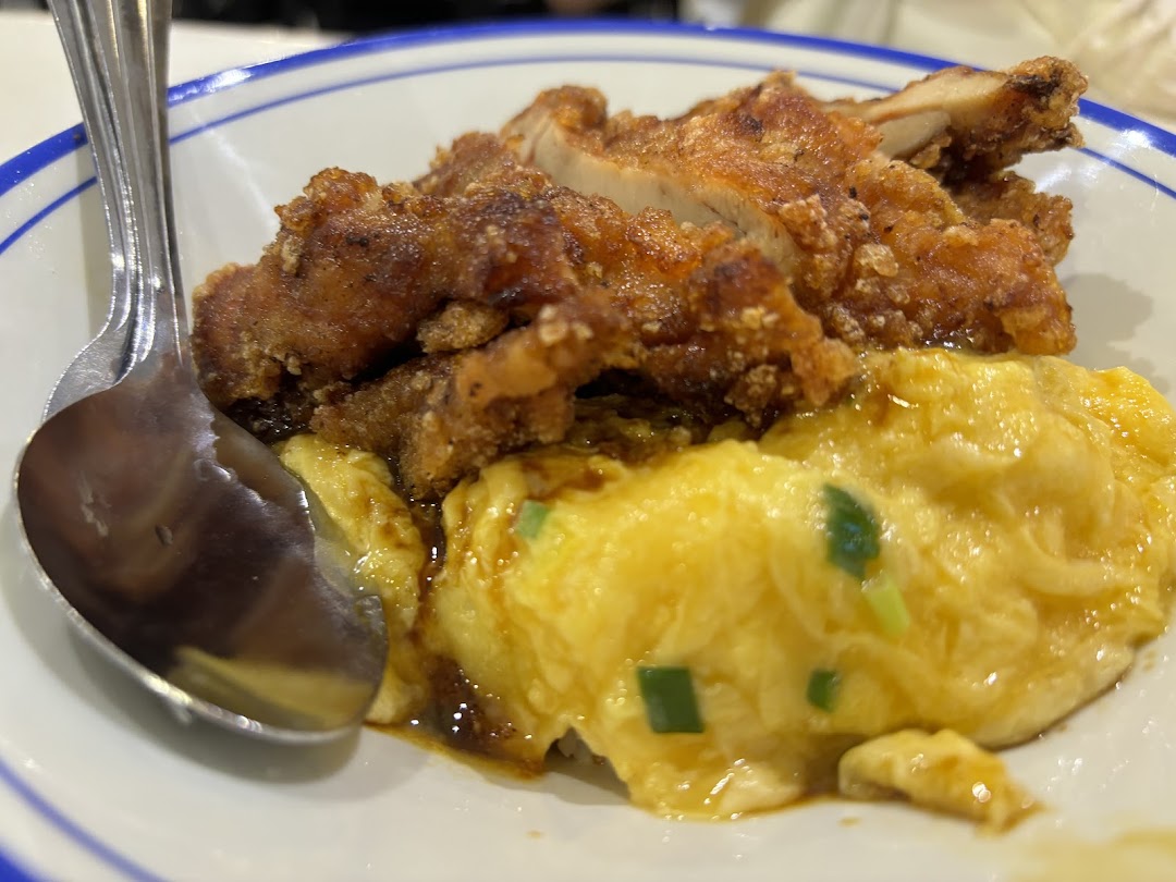 A close-up of crispy fried chicken served with fluffy scrambled eggs in a bowl.
