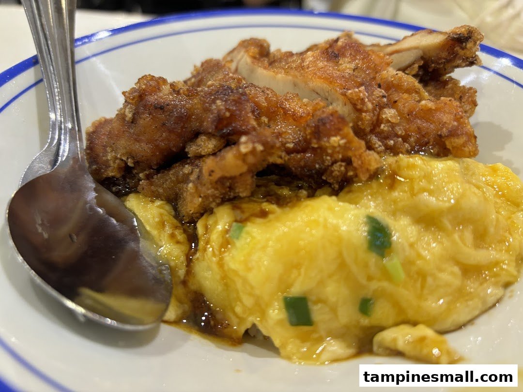 A close-up of crispy fried chicken served with fluffy scrambled eggs in a bowl.