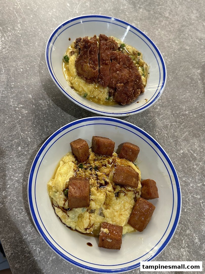Two bowls of scrambled egg rice, one with fried chicken cutlet and one with spam.