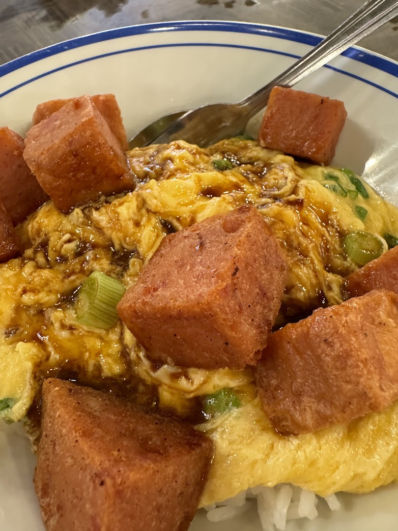 A close-up of scrambled egg rice topped with crispy fried spam cubes and a savory sauce.