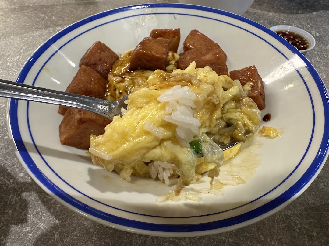 A close-up of scrambled egg rice with spam, served in a classic blue-rimmed bowl.