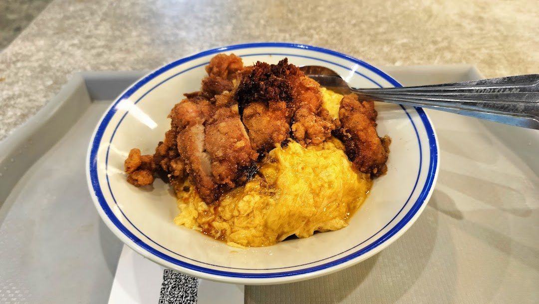 A delicious bowl of scrambled egg rice topped with crispy fried chicken, served on a tray.