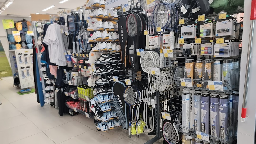 An aisle in Decathlon showcasing sports shoes, badminton rackets, shuttlecocks, and athletic apparel.