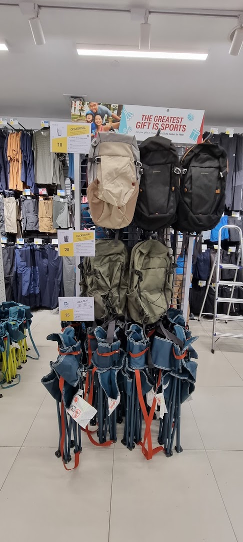Interior display at Decathlon featuring various backpacks, folding chairs, and sports apparel on racks.