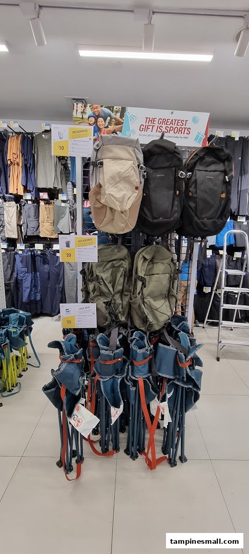 Interior display at Decathlon featuring various backpacks, folding chairs, and sports apparel on racks.