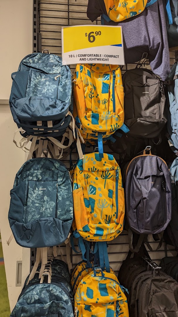 A display of colorful Decathlon backpacks, including patterned and solid designs, with a visible price tag.