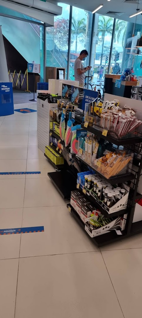 Interior view of Decathlon showing sports nutrition products, accessories, and a customer browsing.