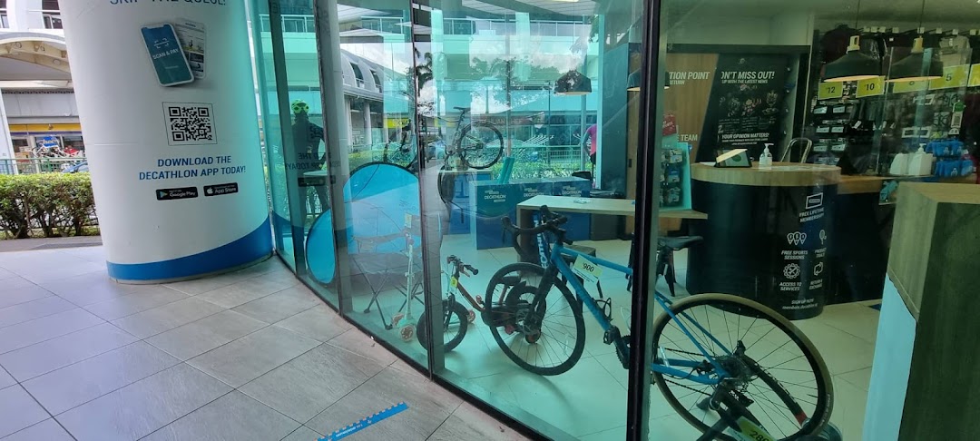 The glass facade of Decathlon, showcasing bicycles and an app download sign at the entrance.