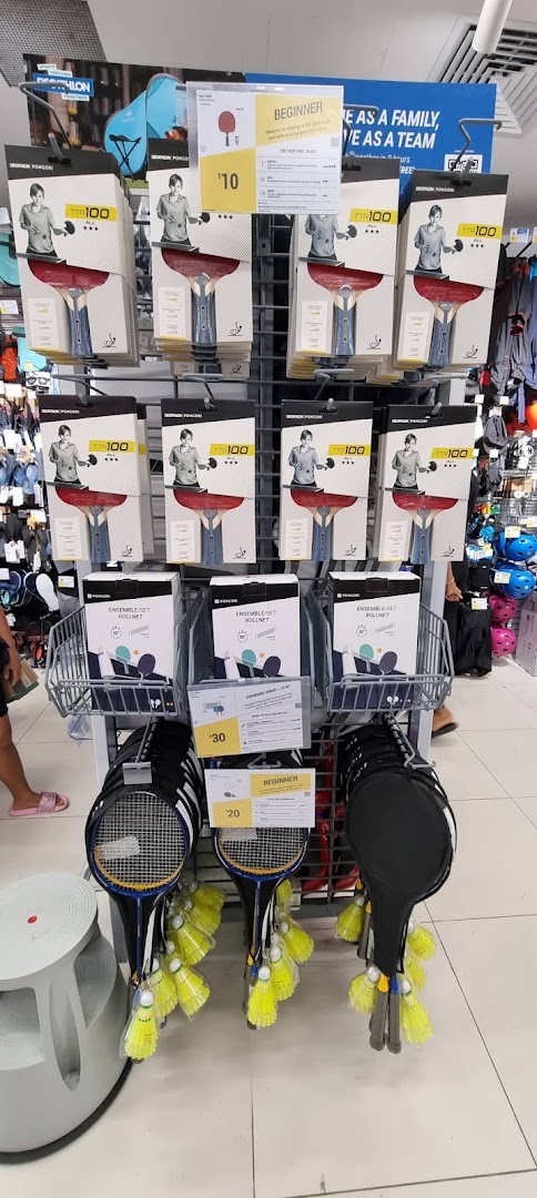 A retail display at Decathlon featuring table tennis rackets and badminton sets.