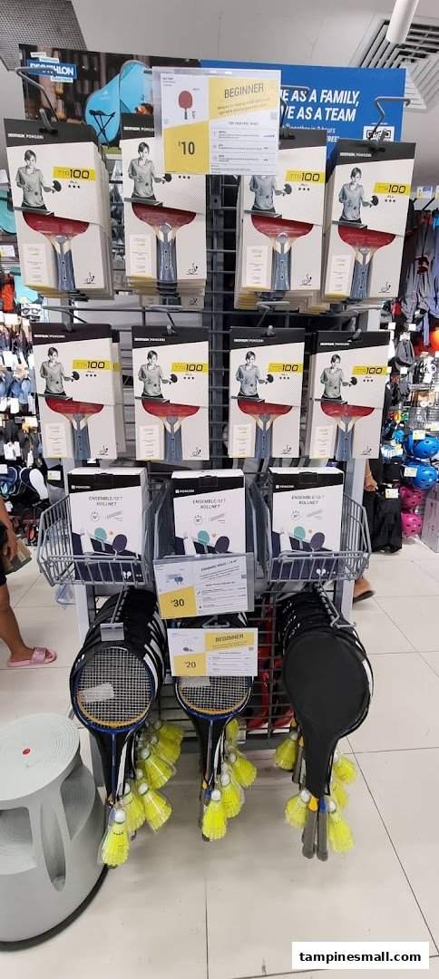A retail display at Decathlon featuring table tennis rackets and badminton sets.