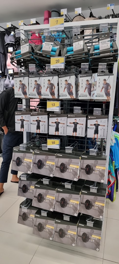 A display of fitness equipment, including ab wheels, suspension trainers, and push-up bars, inside a Decathlon store.