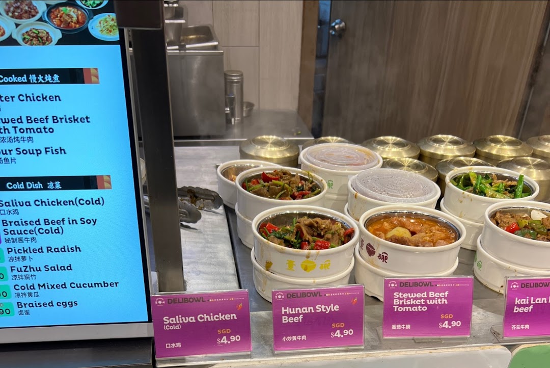 A digital menu board and a display of various hot and cold dishes in containers.