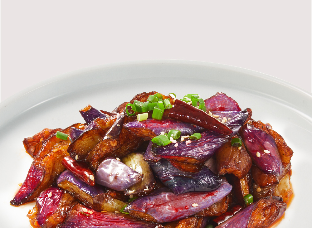A vibrant dish of stir-fried eggplant with chili, sesame seeds, and green onions.