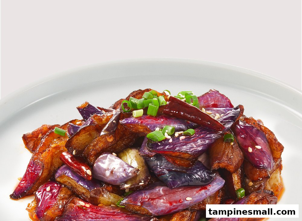 A vibrant dish of stir-fried eggplant with chili, sesame seeds, and green onions.
