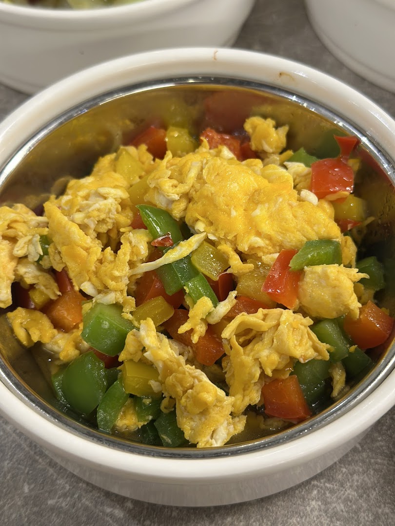 A vibrant bowl of scrambled eggs mixed with diced red, yellow, and green bell peppers.
