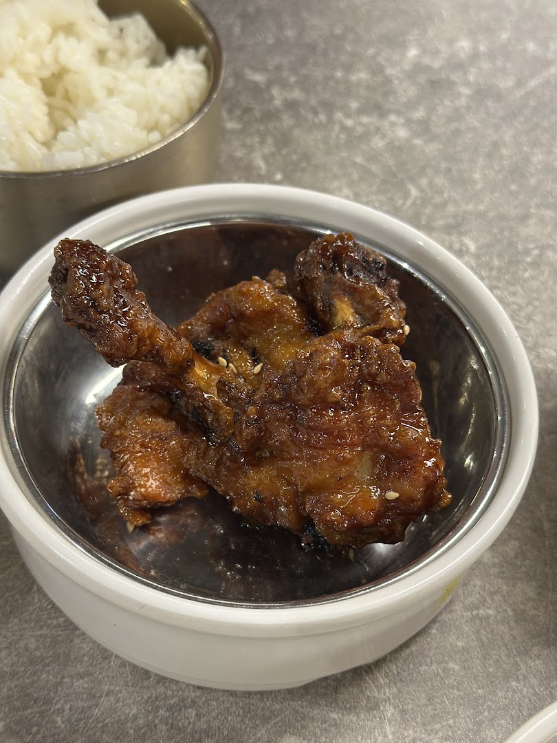 Close-up of glazed chicken pieces with sesame seeds, served with a side of white rice.
