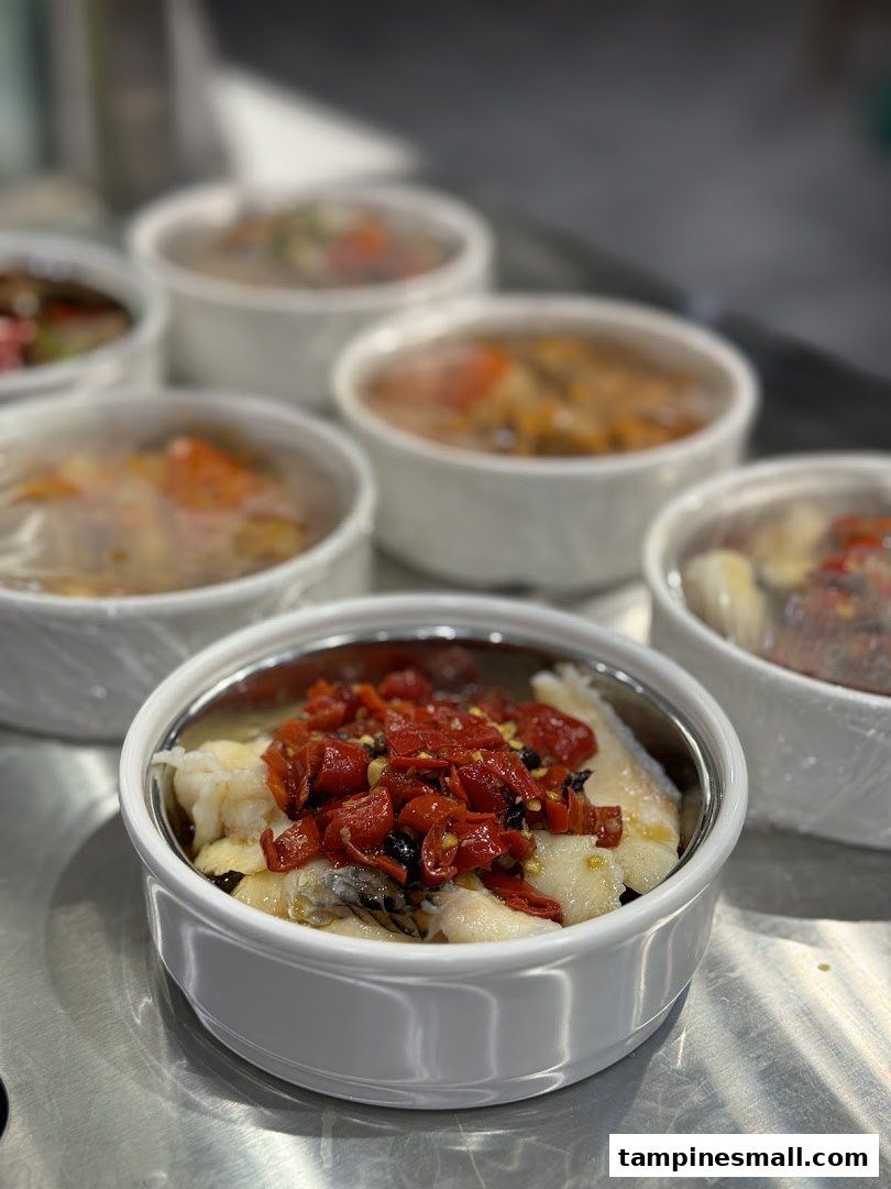 Close-up of several bowls of freshly prepared food, featuring a dish with fish and red peppers.