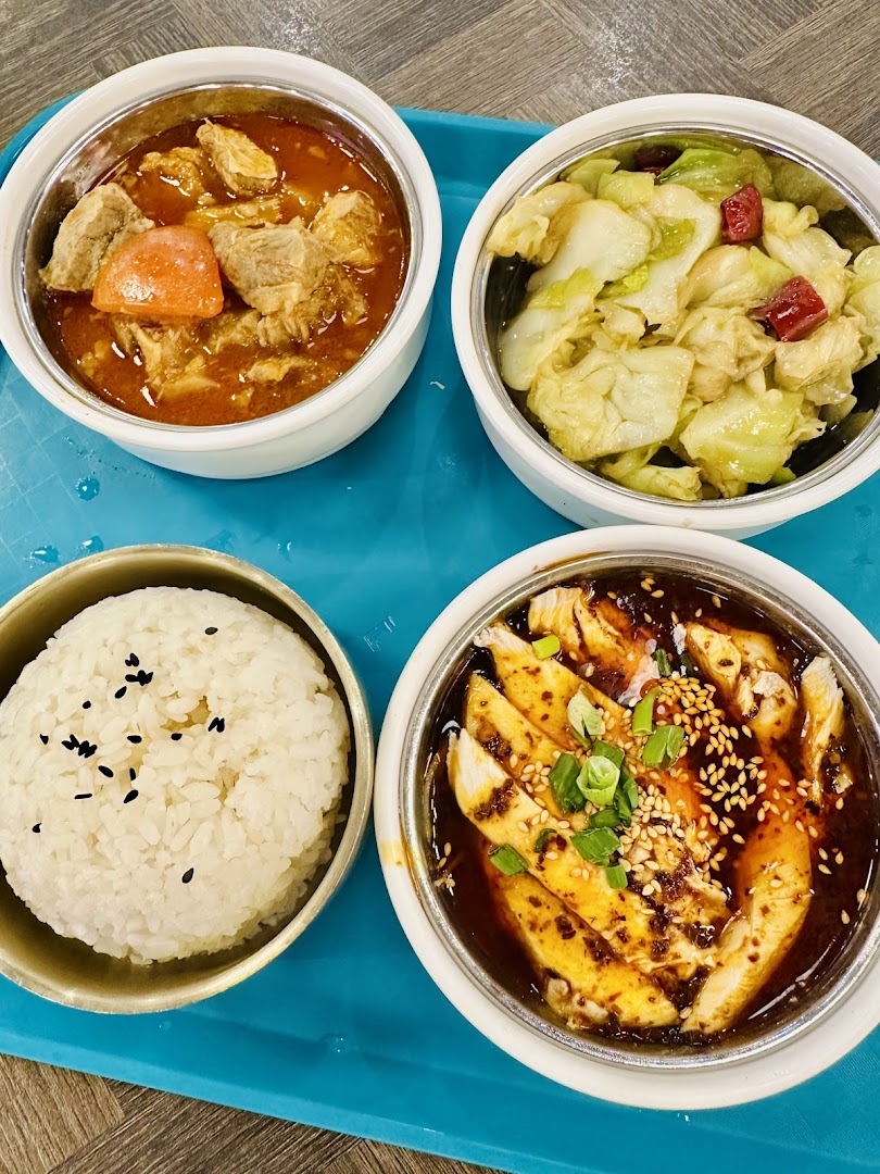 Four bowls of delicious Asian-inspired dishes, including rice, chicken, stew, and vegetables, served on a blue tray.