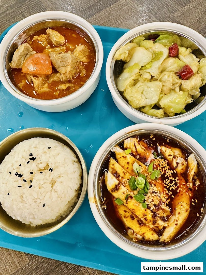 Four bowls of delicious Asian-inspired dishes, including rice, chicken, stew, and vegetables, served on a blue tray.