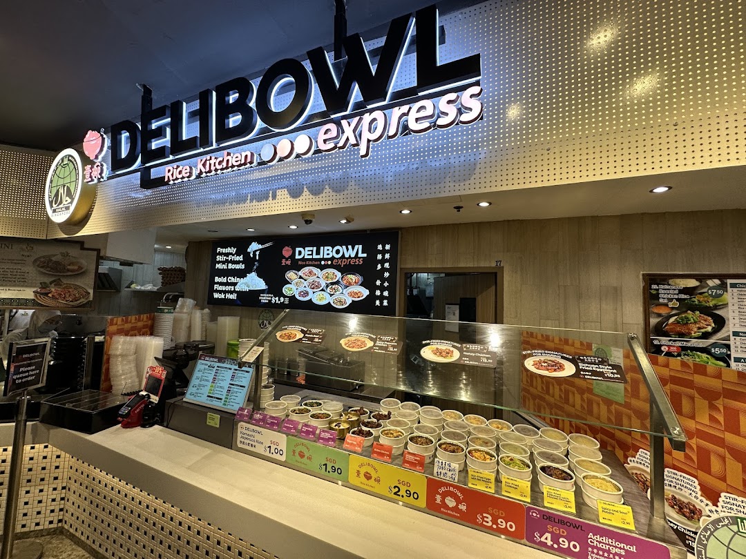 The illuminated storefront and counter of Delibowl Rice Kitchen Express, showcasing food displays.