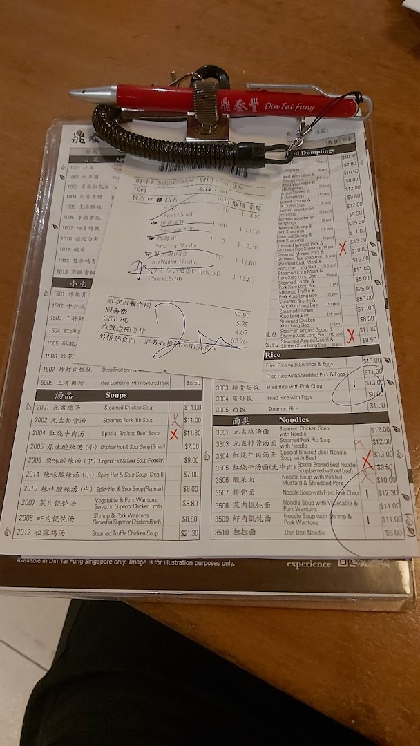 A close-up view of Din Tai Fung's menu on a clipboard with a pen and a receipt.