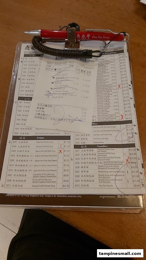 A close-up view of Din Tai Fung's menu on a clipboard with a pen and a receipt.