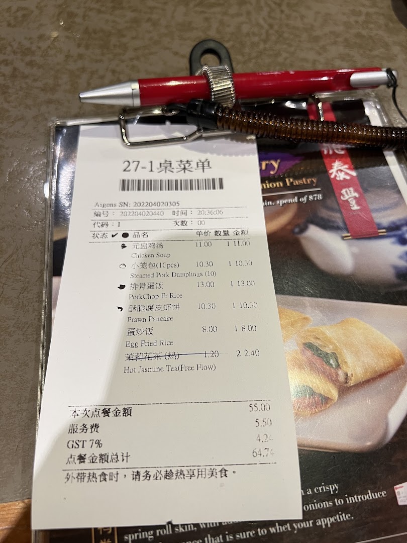 A close-up of a Din Tai Fung order slip with a pen, showing various menu items and prices.