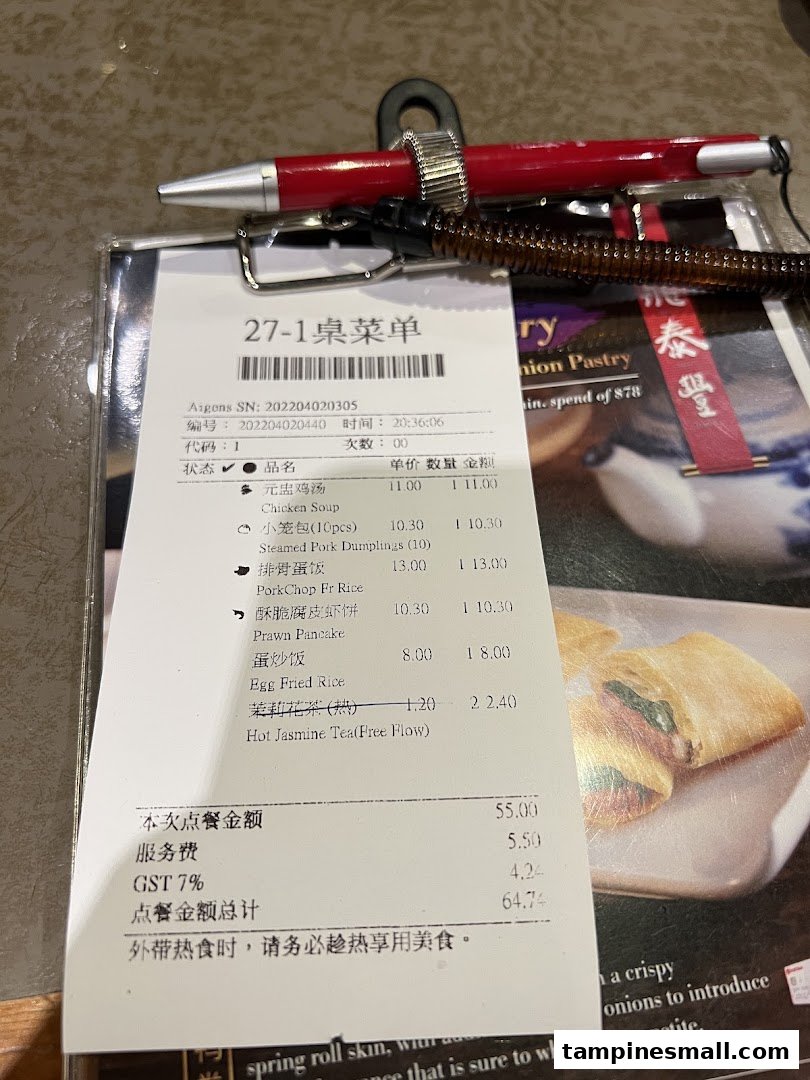 A close-up of a Din Tai Fung order slip with a pen, showing various menu items and prices.