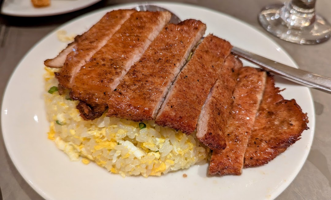 A delicious plate of sliced pork chop served over golden fried rice.