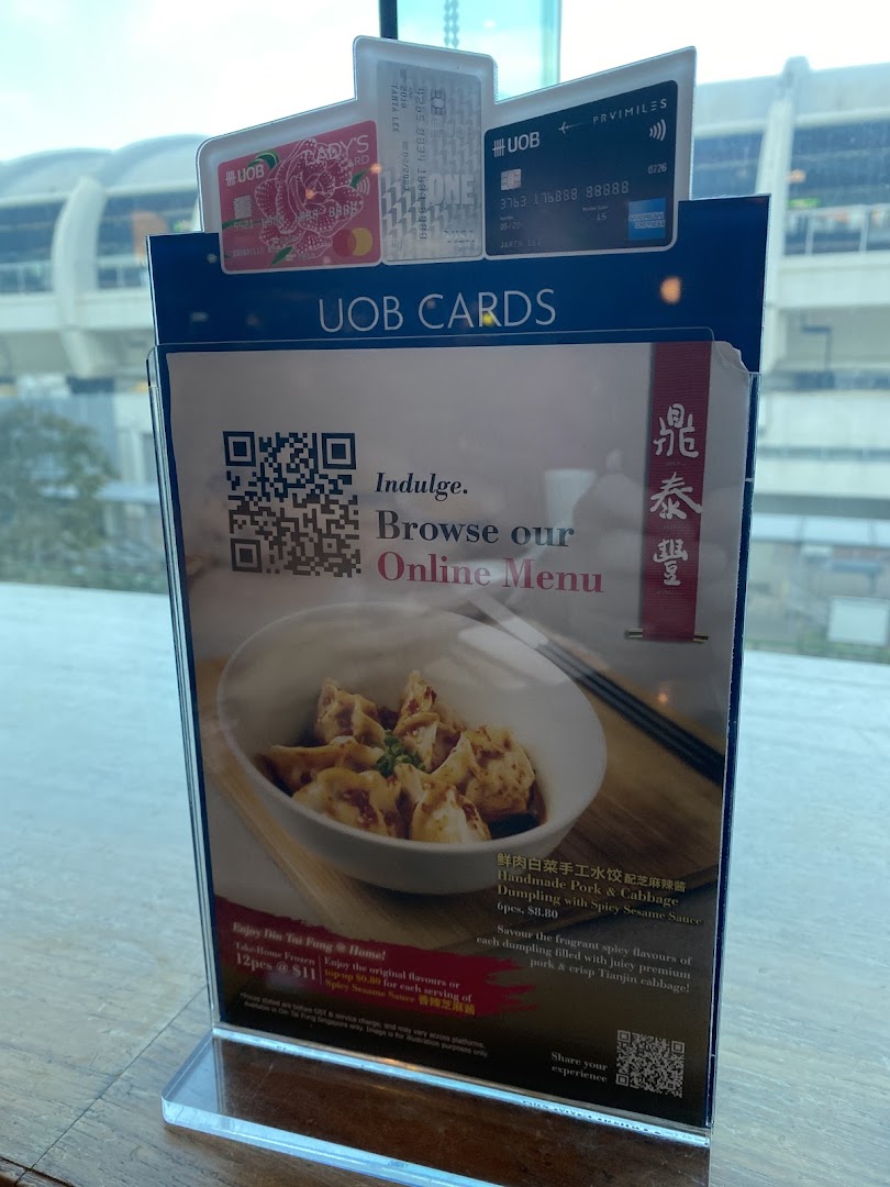 A Din Tai Fung table display featuring Handmade Pork & Cabbage Dumplings, take-home options, and UOB card promotions.