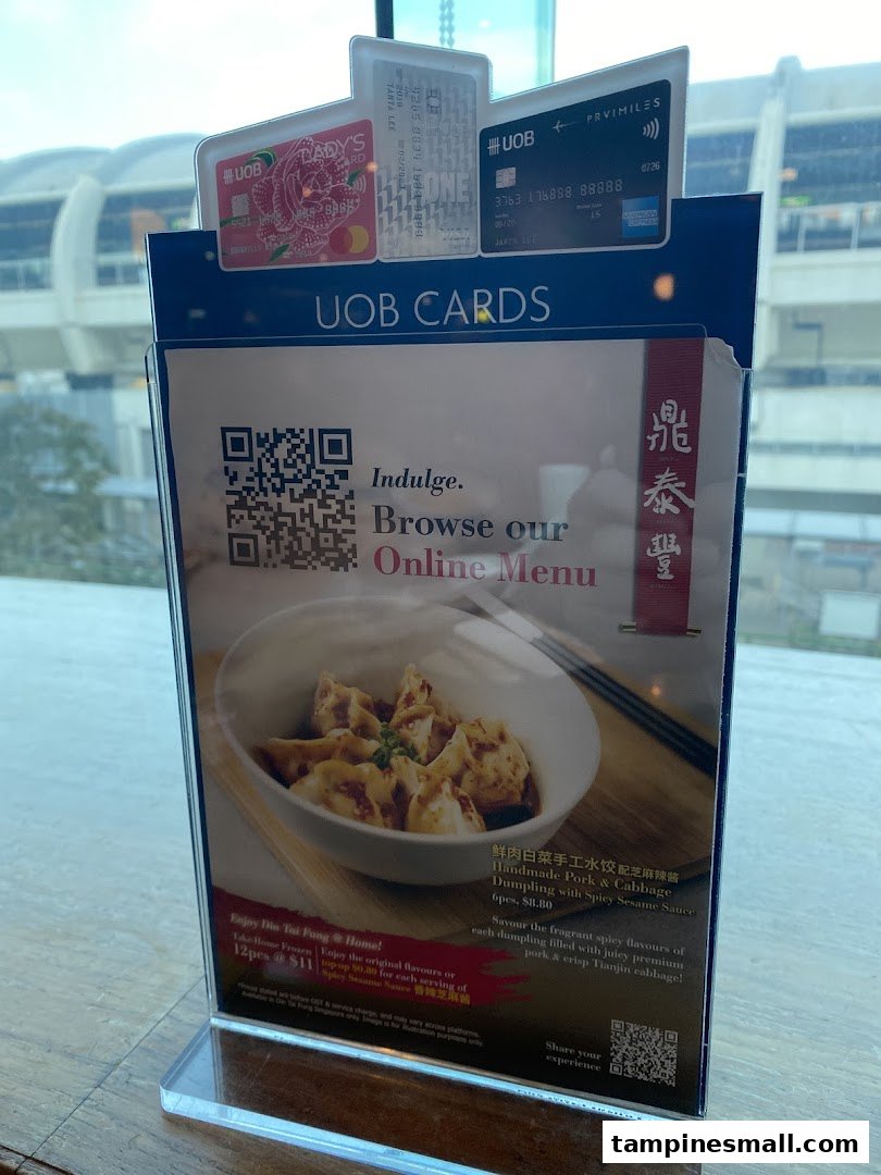 A Din Tai Fung table display featuring Handmade Pork & Cabbage Dumplings, take-home options, and UOB card promotions.